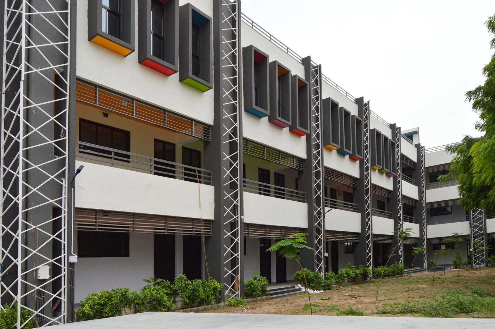 - Exterior of Mehsana Taluka Primary Kumar School showcasing modern sustainable school architecture and dynamic facade in Mehsana, Gujarat - Aerial view of the school campus highlighting green landscape, rainwater harvesting tanks, and shaded walkways - Interior of a flexible classroom with modular furniture, interactive tech stations, and natural light - Collaborative learning zone at Mehsana Taluka Primary Kumar School designed for student creativity and group projects - Solar panels atop the school roof and landscaped courtyard illustrating eco-friendly school design