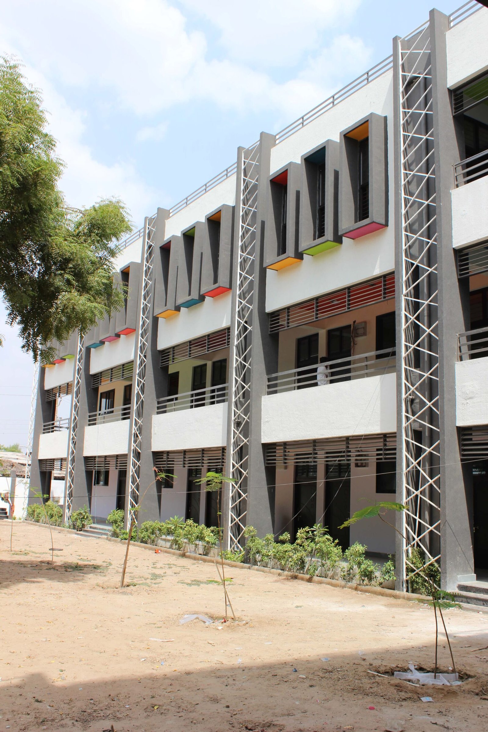 - Exterior of Mehsana Taluka Primary Kumar School showcasing modern sustainable school architecture and dynamic facade in Mehsana, Gujarat - Aerial view of the school campus highlighting green landscape, rainwater harvesting tanks, and shaded walkways - Interior of a flexible classroom with modular furniture, interactive tech stations, and natural light - Collaborative learning zone at Mehsana Taluka Primary Kumar School designed for student creativity and group projects - Solar panels atop the school roof and landscaped courtyard illustrating eco-friendly school design