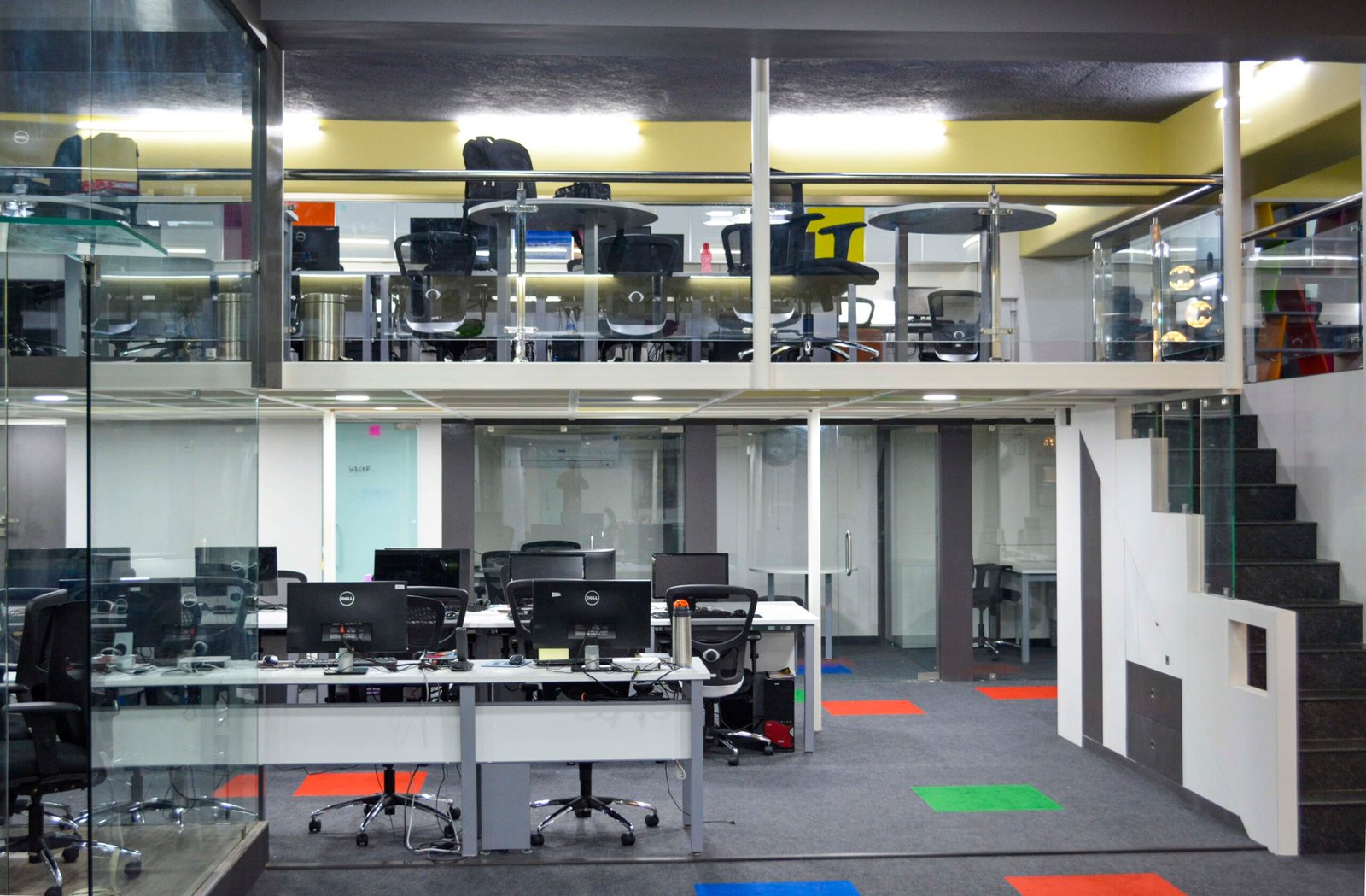 - Entrance view of MultiDots Office showcasing a vibrant reception area with colourful wall graphics - Open-plan workstation with ergonomic desks and bright accent lighting - Collaborative breakout zone featuring informal seating pods and dynamic wall art - Smart conference room equipped with large digital screens and modern furnishings - Relaxation corner with lounge chairs and greenery creating a calm retreat