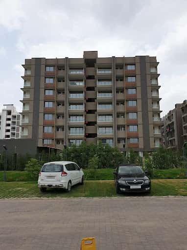 - Exterior view of Prime Status mixed-use towers with illuminated façades along S.G. Highway - Aerial perspective showing residential blocks above street-level commercial units at Prime Status - Balcony view from a 3.5 BHK apartment overlooking Ahmedabad’s cityscape - Ground-level shot of vibrant storefronts and pedestrian plaza at Prime Status - Sleek lobby interior of Prime Status featuring contemporary furnishings and landscaped accents
