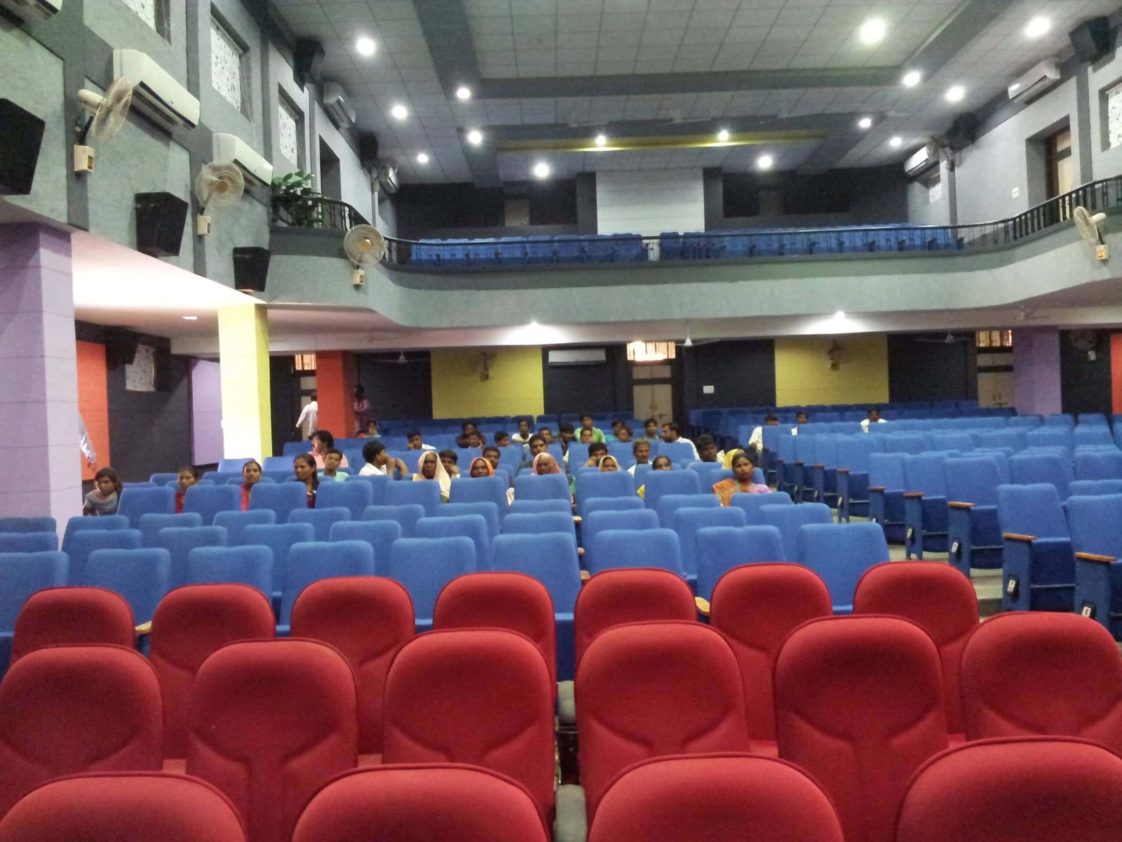 - Front elevation of the restored Sardar Townhall in Rajpipla, showcasing the heritage façade with ornate cornices and columns - Interior view of the refurbished hall with vibrant wall murals, contemporary seating, and updated lighting fixtures - Close-up of decorative plasterwork and restored wooden beams highlighting the building’s historical craftsmanship - Auditorium perspective featuring the renovated stage, modern AV equipment, and flexible seating layout - Nighttime shot of Sardar Townhall illuminated to accentuate architectural details and the entrance canopy