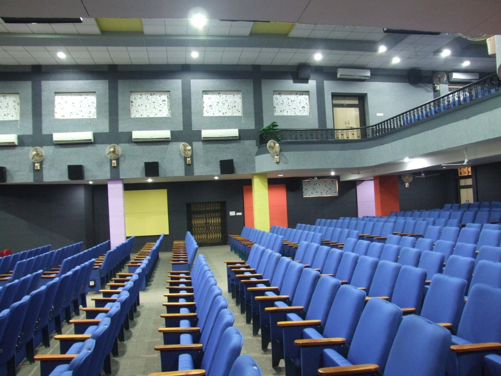 - Front elevation of the restored Sardar Townhall in Rajpipla, showcasing the heritage façade with ornate cornices and columns - Interior view of the refurbished hall with vibrant wall murals, contemporary seating, and updated lighting fixtures - Close-up of decorative plasterwork and restored wooden beams highlighting the building’s historical craftsmanship - Auditorium perspective featuring the renovated stage, modern AV equipment, and flexible seating layout - Nighttime shot of Sardar Townhall illuminated to accentuate architectural details and the entrance canopy