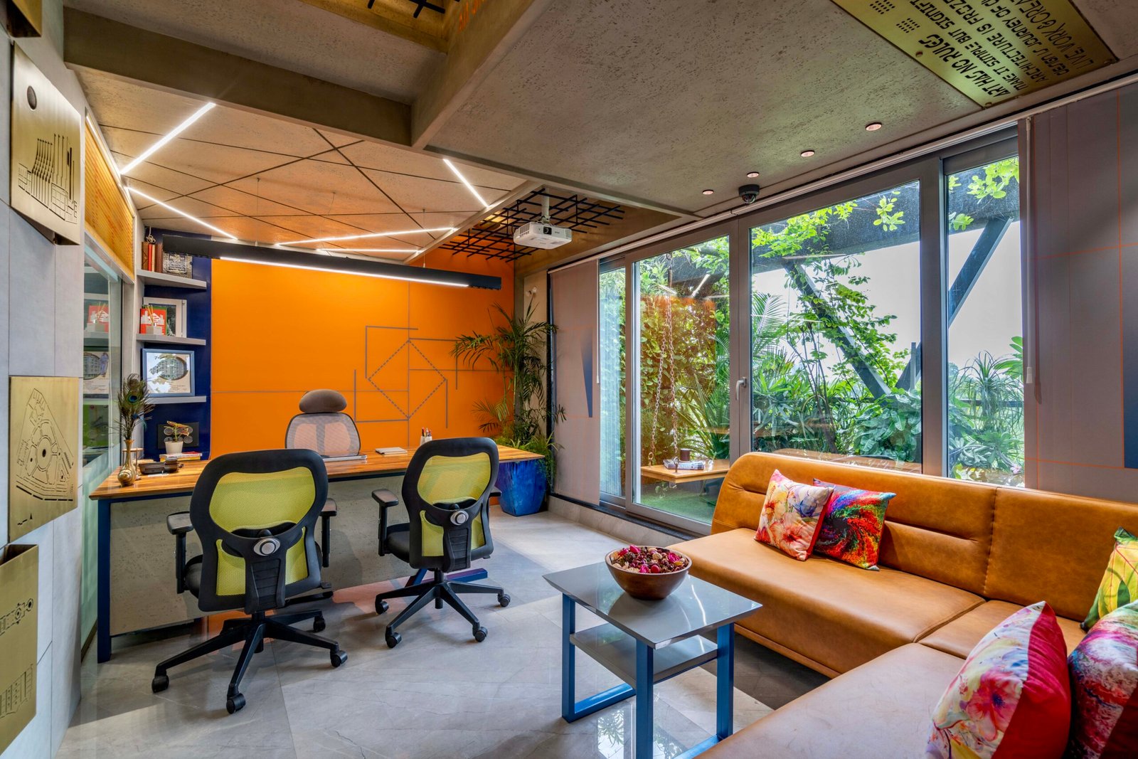-Exterior shot of Vastu Nirman Architects’ Office in Ahmedabad featuring a minimalist façade, green planter boxes, and entrance signage -Reception area with vibrant accent wall, sleek minimalist desk, and eco-friendly décor elements -Open-plan collaborative workspace showing adjustable desks, colorful partitions, and abundant natural light -Living wall installation and indoor plant clusters creating a green oasis within the office interior -Flexible brainstorming zone with modular seating, writable wall panels, and sustainable lighting fixtures