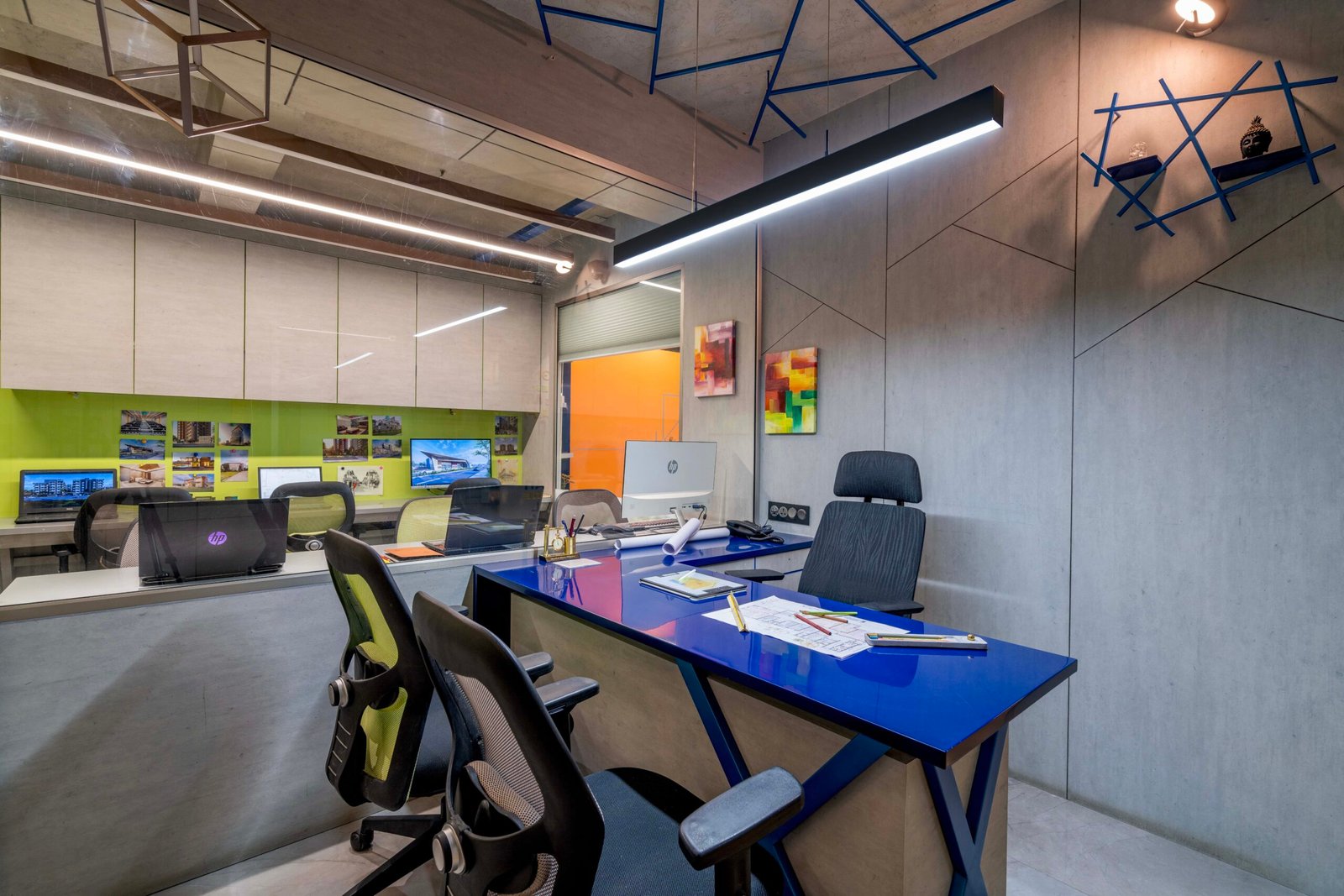 -Exterior shot of Vastu Nirman Architects’ Office in Ahmedabad featuring a minimalist façade, green planter boxes, and entrance signage -Reception area with vibrant accent wall, sleek minimalist desk, and eco-friendly décor elements -Open-plan collaborative workspace showing adjustable desks, colorful partitions, and abundant natural light -Living wall installation and indoor plant clusters creating a green oasis within the office interior -Flexible brainstorming zone with modular seating, writable wall panels, and sustainable lighting fixtures