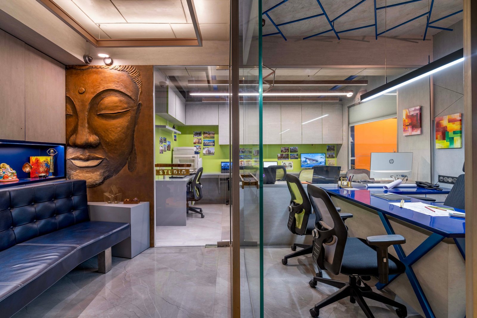 -Exterior shot of Vastu Nirman Architects’ Office in Ahmedabad featuring a minimalist façade, green planter boxes, and entrance signage -Reception area with vibrant accent wall, sleek minimalist desk, and eco-friendly décor elements -Open-plan collaborative workspace showing adjustable desks, colorful partitions, and abundant natural light -Living wall installation and indoor plant clusters creating a green oasis within the office interior -Flexible brainstorming zone with modular seating, writable wall panels, and sustainable lighting fixtures